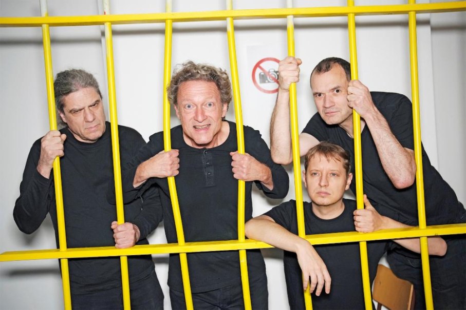 Vier M&auml;nner in schwarzen Hemden posieren hinter gelben Gitterst&auml;ben. Sie schauen ernst und konzentriert in die Kamera., &copy; Foto South Quartett