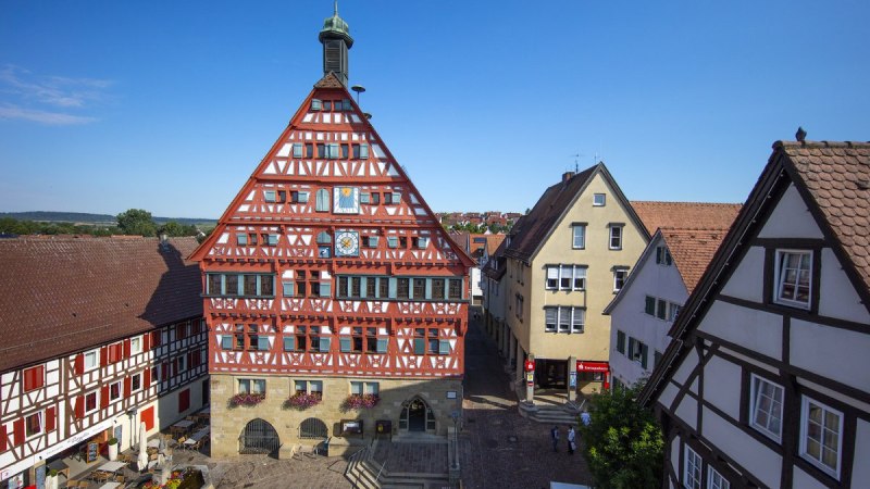Fachwerk-Rathaus in Gro&szlig;bottwar, umgeben von historischen Geb&auml;uden. Der Platz ist mit Blumen geschm&uuml;ckt, der Himmel ist klar und blau., &copy; Stuttgart Marketing Mende
