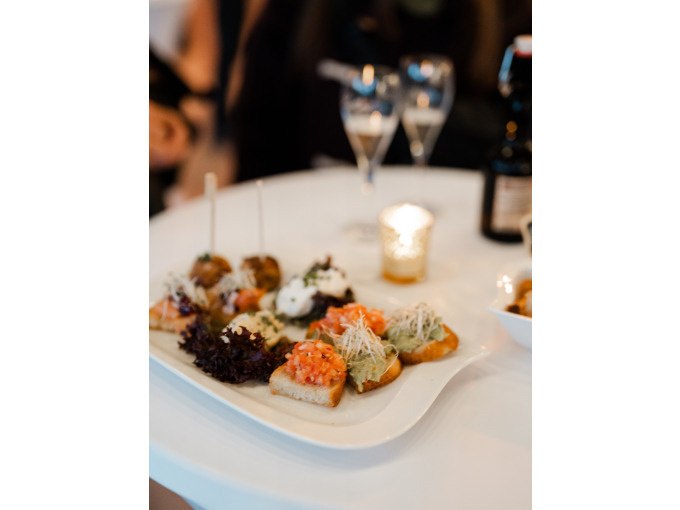 Vorspeisenteller mit Canapés auf weißem Tisch, zwei Gläser und Kerze im Hintergrund, romantische Atmosphäre., © Cool-Tours StattReisen