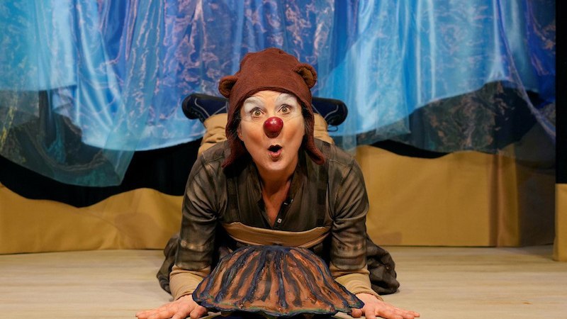 Person in Kost&uuml;m mit roter Nase und brauner M&uuml;tze vor Muschelattrappe auf B&uuml;hne. Hintergrund mit blauem Stoff dekoriert., &copy; FILharmonie Filderstadt