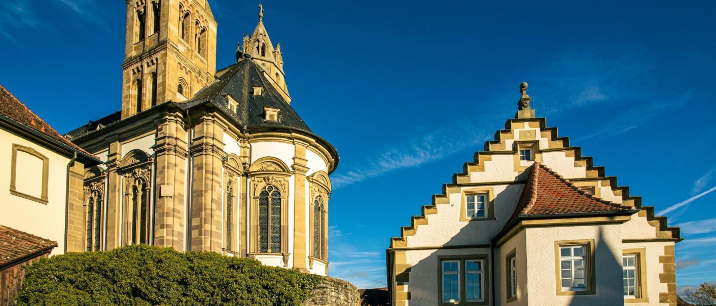Die Großcomburg in Schwäbisch Hall zeigt beeindruckende Architektur mit einem Turm und einem Gebäude mit Treppengiebel unter klarem, blauem Himmel., © Stuttgart-Marketing GmbH, Sarah Schmid