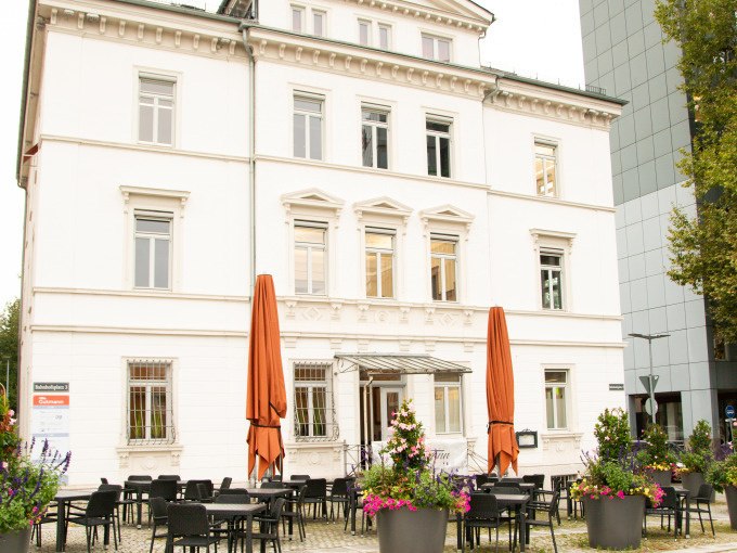 Historisches Geb&auml;ude mit wei&szlig;er Fassade, davor ein Caf&eacute; mit Tischen und Pflanzen. Die Architektur erinnert an die fr&uuml;here Weberei Gutmann., &copy; Stadt G&ouml;ppingen