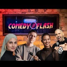 Vier Personen mit Mikrofonen stehen vor einem Comedyflash-Logo auf einer Backsteinwand. Sie l&auml;cheln und scheinen bereit f&uuml;r eine Stand-up-Comedy-Show., &copy; links im Bild