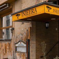 Restaurant Injeera mit gelbem Schild und Holzzaun, bietet afrikanische K&uuml;che an. Au&szlig;enansicht mit Laternen und Pflanzen., &copy; SMG, Sarah Schmid