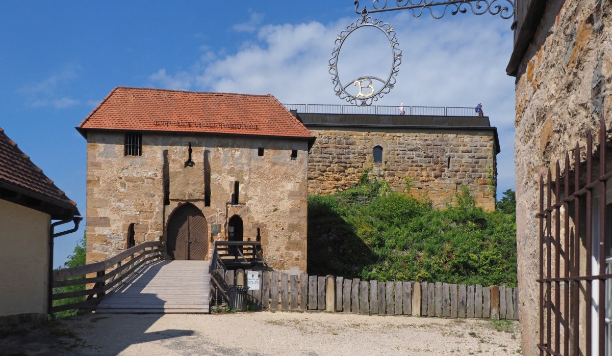 Die Burgruine Hohenrechberg zeigt ein altes Torhaus mit rotem Ziegeldach und eine massive Steinmauer, umgeben von grüner Vegetation., © Foto: Walter Laible