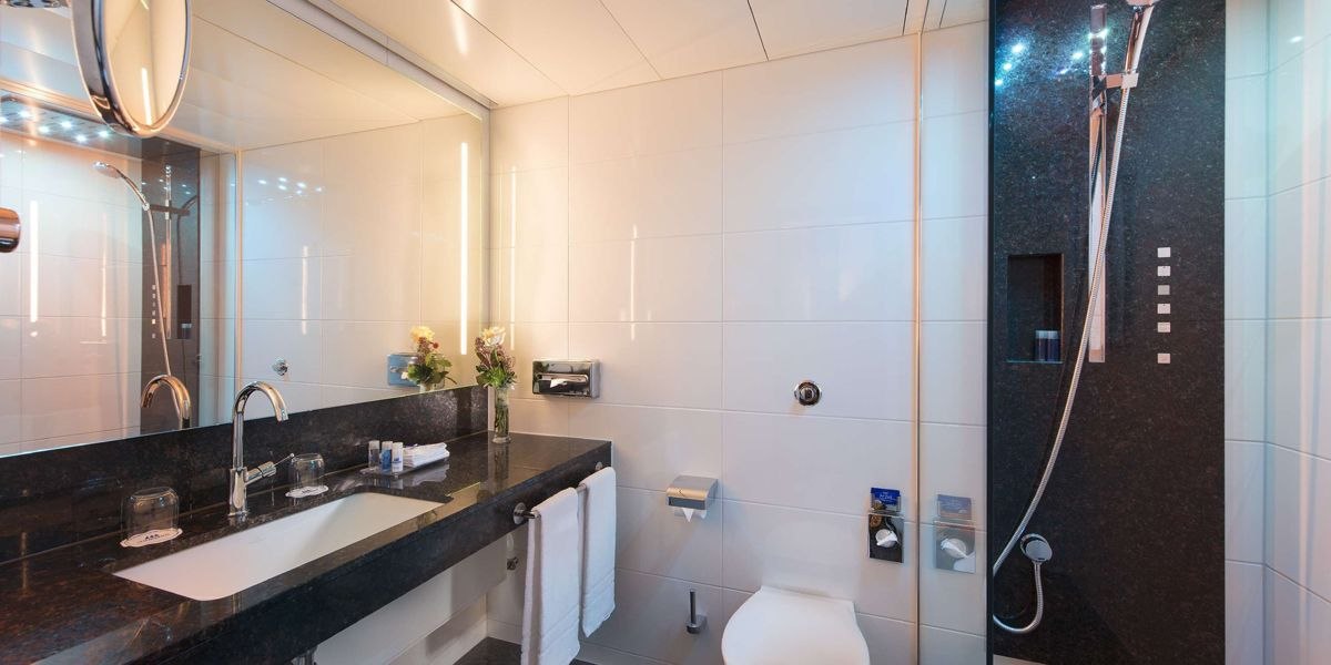 Modernes Badezimmer mit großem Spiegel, Waschtisch, Dusche und Toilette. Dezente Beleuchtung und elegante Armaturen., © Maritim Hotelgesellschaft mbH
