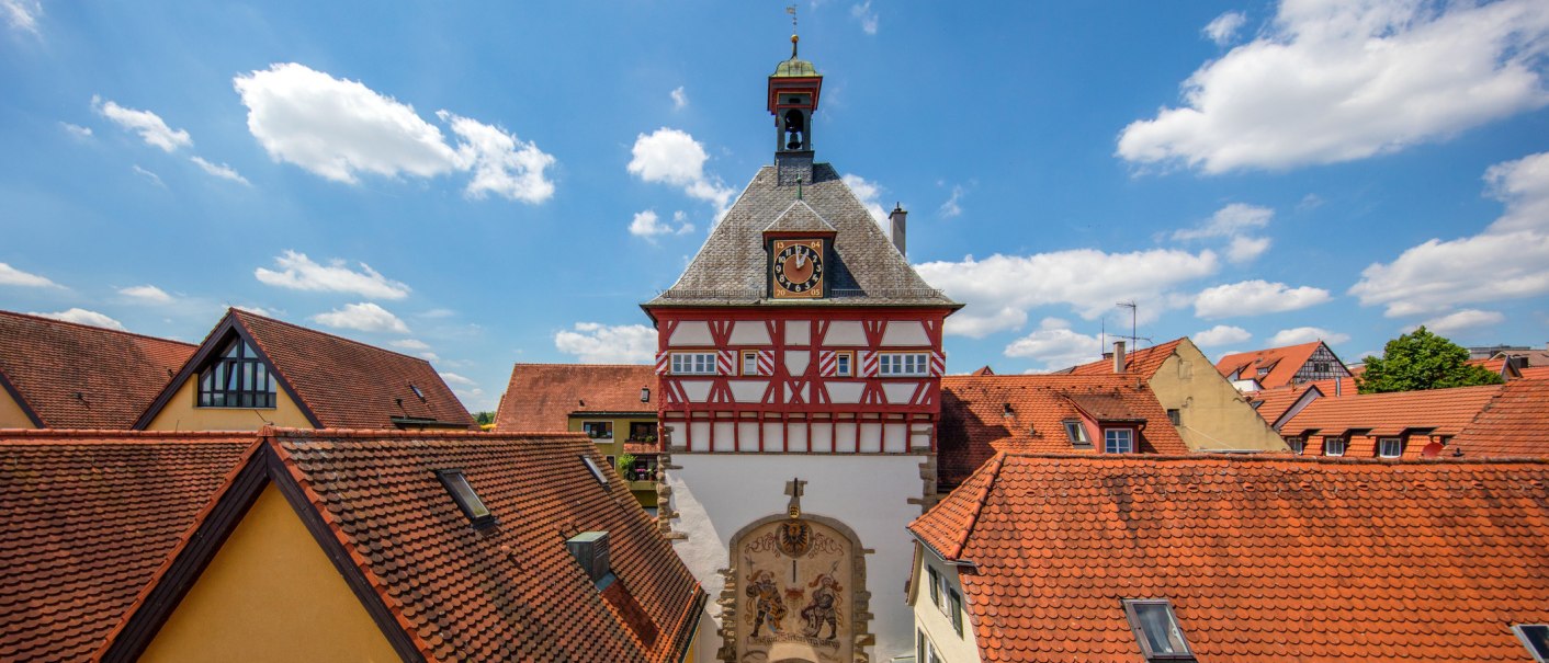 Fachwerkgebäude mit Uhrturm in Bietigheim-Bissingen, umgeben von roten Ziegeldächern und blauem Himmel., © SMG, Achim Mende Fachwerkgebäude mit Uhrturm in Bietigheim-Bissingen, umgeben von roten Ziegeldächern und blauem Himmel., © SMG, Achim Mende