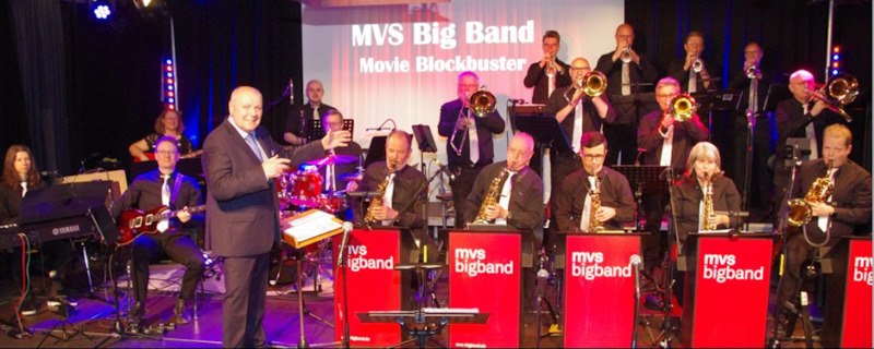 Die MVS Big Band performt auf einer B&uuml;hne. Der Dirigent steht vorne, w&auml;hrend die Musiker im Hintergrund spielen. Ein Banner zeigt den Bandnamen., &copy; Interessengemeinschaft Kultur Sindelfingen / B&ouml;blingen e.V.