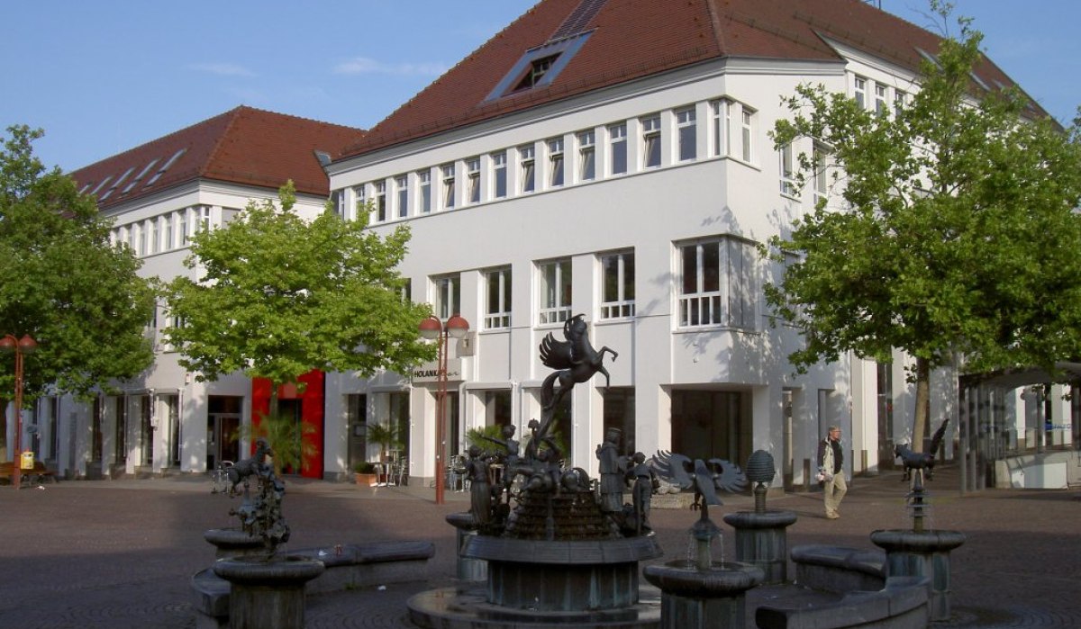 Ein Platz mit einem kunstvollen Brunnen und einem weißen Gebäude im Hintergrund. Bäume und ein blauer Himmel umrahmen die Szene., © Natur.Nah. Schönbuch & Heckengäu