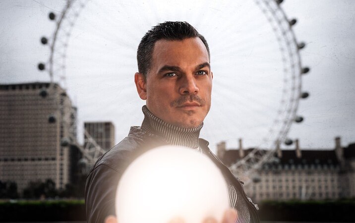 Ein Mann in Lederjacke h&auml;lt eine leuchtende Kugel vor dem London Eye. Der Himmel ist bew&ouml;lkt, und die Szene wirkt mystisch., &copy; Mercedes-Benz AG