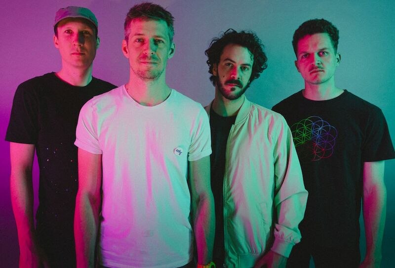 Vier M&auml;nner posieren vor einem farbigen Hintergrund, beleuchtet in rosa und gr&uuml;nem Licht. Sie tragen l&auml;ssige Kleidung., &copy; Stadthalle Leonberg