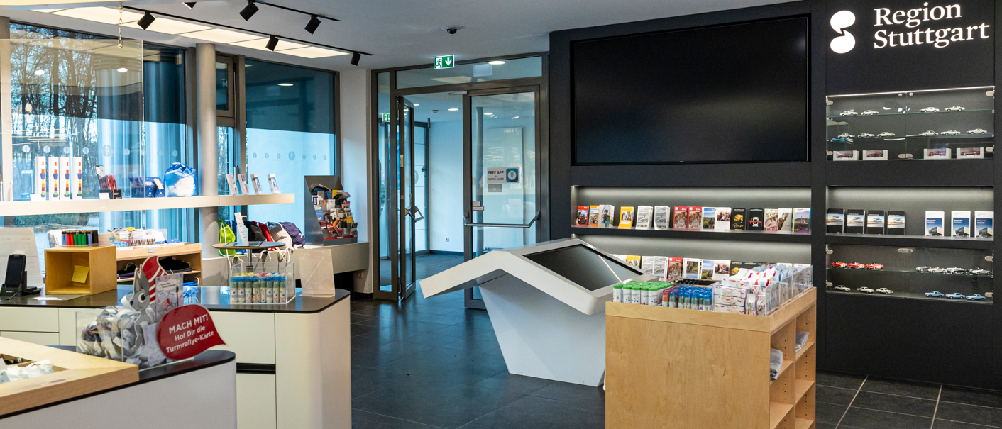 Tourist Info im Fernsehturm Stuttgart mit Broschüren, Souvenirs und einem großen Bildschirm. Modernes Design mit Informationsmaterial zur Region Stuttgart., © Stuttgart-Marketing GmbH, Sarah Schmid