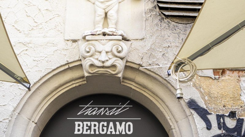 Steinfigur &uuml;ber einem Torbogen mit der Aufschrift 'transit BERGAMO'. Graffiti und verwitterte Wand im Hintergrund., &copy; SMG, Sarah Schmid
