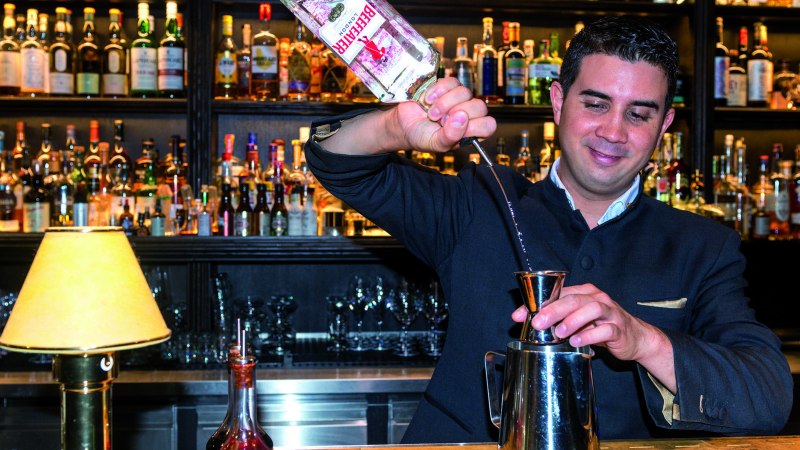 Ein Barkeeper gie&szlig;t Gin in einen Jigger. Im Hintergrund sind zahlreiche Flaschen in einem Regal zu sehen., &copy; TMBW, Gregor Lengler