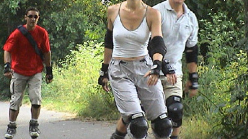 Drei Personen fahren auf einem Waldweg Inlineskates. Sie tragen Schutzkleidung und lächeln. Die Umgebung ist grün und bewaldet., © Natur.Nah. Schönbuch & Heckengäu