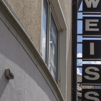 Ein Schild mit der Aufschrift 'WEISS' hängt an einem Gebäude. Der Himmel ist blau mit einigen Wolken. Im Hintergrund sind Dächer zu sehen., © SMG, Sarah Schmid Ein Schild mit der Aufschrift 'WEISS' hängt an einem Gebäude. Der Himmel ist blau mit einigen Wolken. Im Hintergrund sind Dächer zu sehen., © SMG, Sarah Schmid