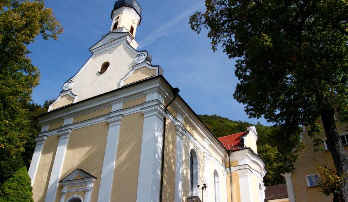 Die Wallfahrtskirche Ave Maria in Deggingen mit gelber Fassade und weißen Säulen, umgeben von Bäumen unter blauem Himmel., © Landkreis Göppingen