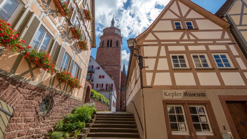 Fachwerkhäuser in der Keplergasse, Weil der Stadt. Das Keplermuseum ist sichtbar, mit einem Kirchturm im Hintergrund und blühenden Blumen an den Fenstern., © SMG, Achim Mende