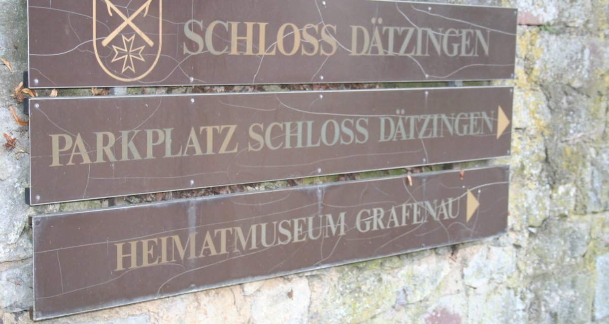Wegweiser aus Holz zeigt Richtung Schloss Dätzingen und Heimatmuseum Grafenau. Schild mit Wappen an einer Steinmauer befestigt., © Natur.Nah. Schönbuch & Heckengäu Wegweiser aus Holz zeigt Richtung Schloss Dätzingen und Heimatmuseum Grafenau. Schild mit Wappen an einer Steinmauer befestigt., © Natur.Nah. Schönbuch & Heckengäu