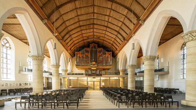 Innenansicht der Martinskirche in Kirchheim unter Teck. Sicht auf die Orgel, hohe Säulen und Sitzreihen. Hölzerne Decke und große Fenster., © SMG, Sarah Schmid