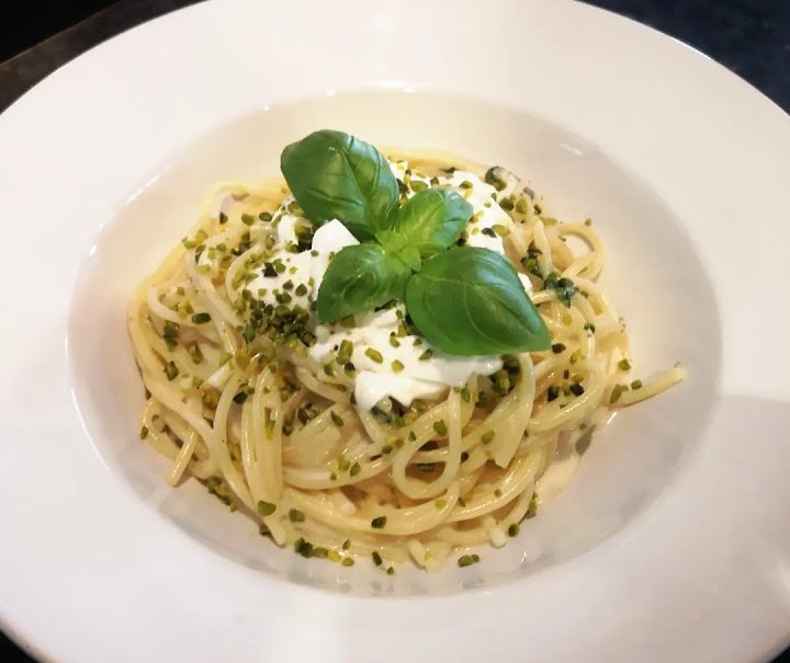 Spaghetti mit Sahnesoße, gehackten Pistazien und Basilikumblättern auf einem weißen Teller serviert., © La buona Forketta Spaghetti mit Sahnesoße, gehackten Pistazien und Basilikumblättern auf einem weißen Teller serviert., © La buona Forketta