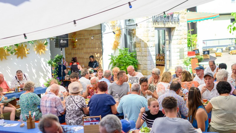 Geselliges Beisammensein im Freien bei Weingut Zaiß. Menschen genießen Essen und Getränke unter einem Sonnensegel., © Weingut Zaiß Geselliges Beisammensein im Freien bei Weingut Zaiß. Menschen genießen Essen und Getränke unter einem Sonnensegel., © Weingut Zaiß