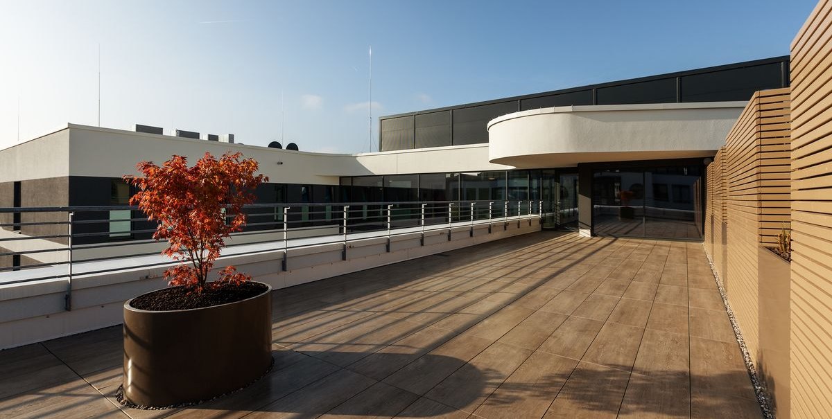 Moderne Terrasse mit Holzfliesen, Geländer und einem kleinen Baum in einem Pflanzkübel. Klare Linien und minimalistisches Design., © Novum Hospitality Moderne Terrasse mit Holzfliesen, Geländer und einem kleinen Baum in einem Pflanzkübel. Klare Linien und minimalistisches Design., © Novum Hospitality