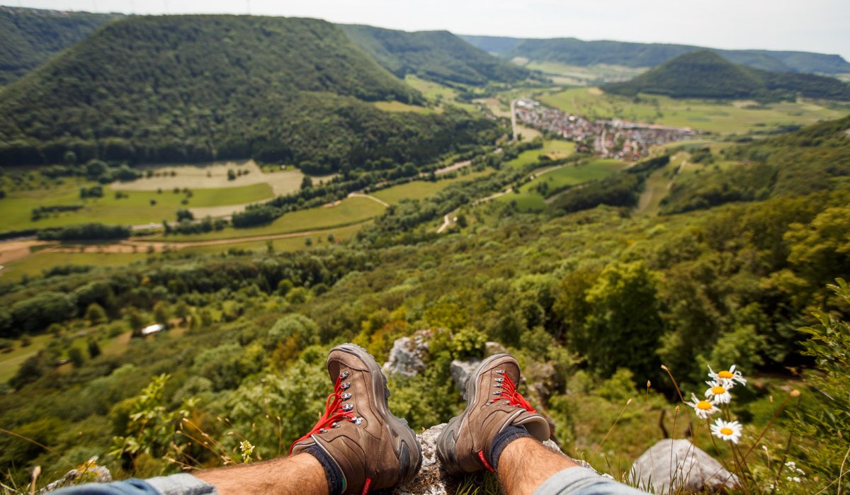 Panoramablick ins Obere Filstal, im Vordergrund Wanderstiefel und Gänseblümchen, im Hintergrund grüne Hügel und ein Dorf., © Landkreis Göppingen Panoramablick ins Obere Filstal, im Vordergrund Wanderstiefel und Gänseblümchen, im Hintergrund grüne Hügel und ein Dorf., © Landkreis Göppingen