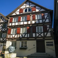 Fachwerkhäuser in Schorndorf bei sonnigem Wetter. Eine Büste steht vor einem der Häuser. Klare blaue Himmel im Hintergrund., © SMG Stuttgart Marketing GmbH - Sarah Schmid