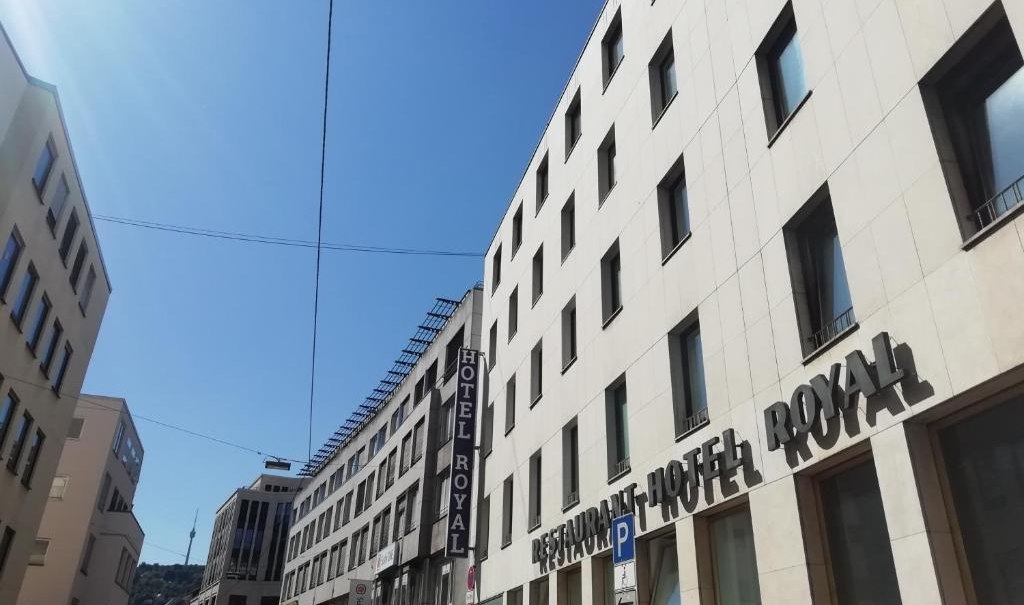 Ein modernes Gebäude mit dem Schriftzug 'Hotel Royal' unter blauem Himmel. Die Straße ist von weiteren Gebäuden gesäumt., © Hotel Royal Ein modernes Gebäude mit dem Schriftzug 'Hotel Royal' unter blauem Himmel. Die Straße ist von weiteren Gebäuden gesäumt., © Hotel Royal