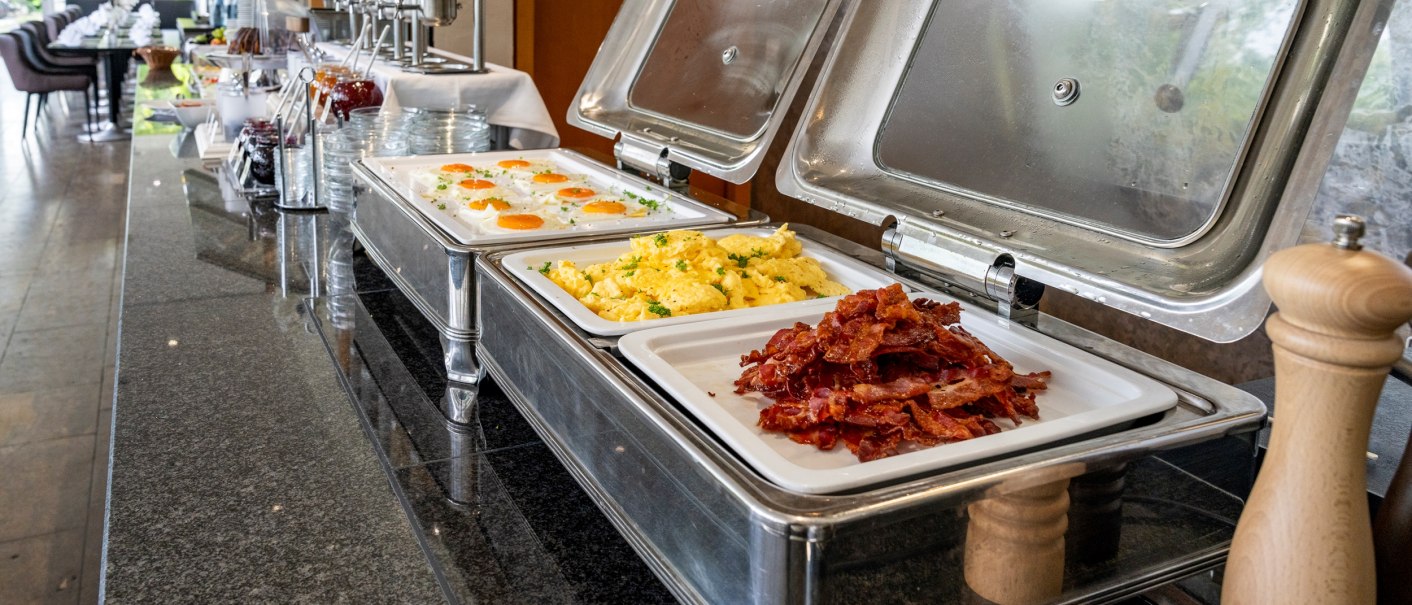 Ein reichhaltiges Frühstücksbuffet mit Spiegeleiern, Rührei und knusprigem Speck in einem eleganten Restaurant., © Plaza Residence Stuttgart-Ditzingen Ein reichhaltiges Frühstücksbuffet mit Spiegeleiern, Rührei und knusprigem Speck in einem eleganten Restaurant., © Plaza Residence Stuttgart-Ditzingen