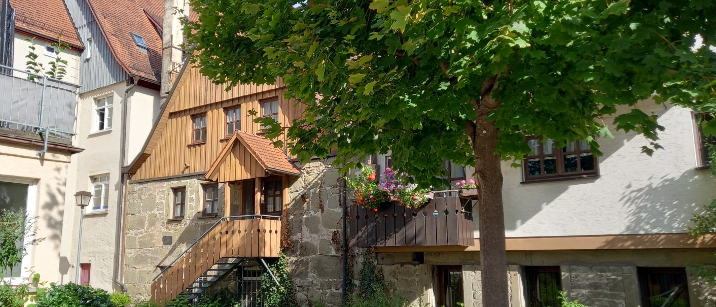 Historische Geb&auml;ude in Gaildorf mit Fachwerk und einem Baum im Vordergrund. Die Au&szlig;enmauern zeigen Reste der alten Stadtmauer. Die Szene zeigt eine ruhige, gr&uuml;ne Umgebung., &copy; Petra Natzkowski