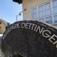 Ein M&uuml;hlstein mit der Aufschrift 'Kulturpark Dettinger' steht vor einem Geb&auml;ude mit der Hausnummer 56. Im Hintergrund ist ein weiteres Geb&auml;ude zu sehen., &copy; PlochingenInfo