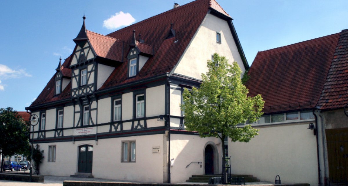 Fachwerkhaus mit rotem Satteldach und dekorativen Giebeln. Ein Baum steht im Vordergrund, der Himmel ist blau mit wenigen Wolken., © Nürtingen - Stuttgart-Marketing GmbH Fachwerkhaus mit rotem Satteldach und dekorativen Giebeln. Ein Baum steht im Vordergrund, der Himmel ist blau mit wenigen Wolken., © Nürtingen - Stuttgart-Marketing GmbH