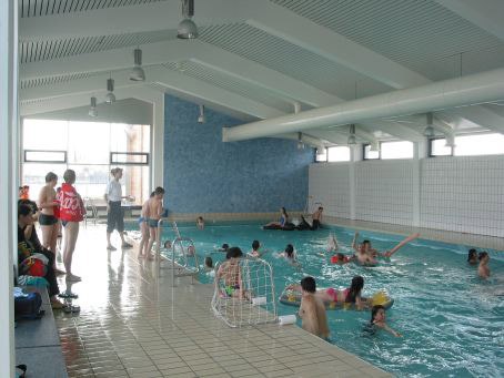 Menschen schwimmen und spielen in einem Hallenbad. Einige stehen am Beckenrand, andere sind im Wasser. Helle, moderne Architektur., © Filder Stadtwerke