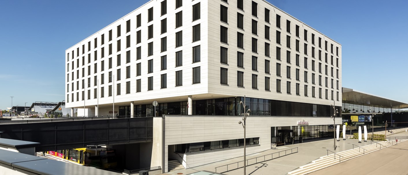 Modernes Gebäude mit Mövenpick-Logo, nahe einem Flughafen oder Messegelände. Klare Linien und große Fenster prägen die Architektur., © Mövenpick Hotel Stuttgart Messe & Congress Modernes Gebäude mit Mövenpick-Logo, nahe einem Flughafen oder Messegelände. Klare Linien und große Fenster prägen die Architektur., © Mövenpick Hotel Stuttgart Messe & Congress