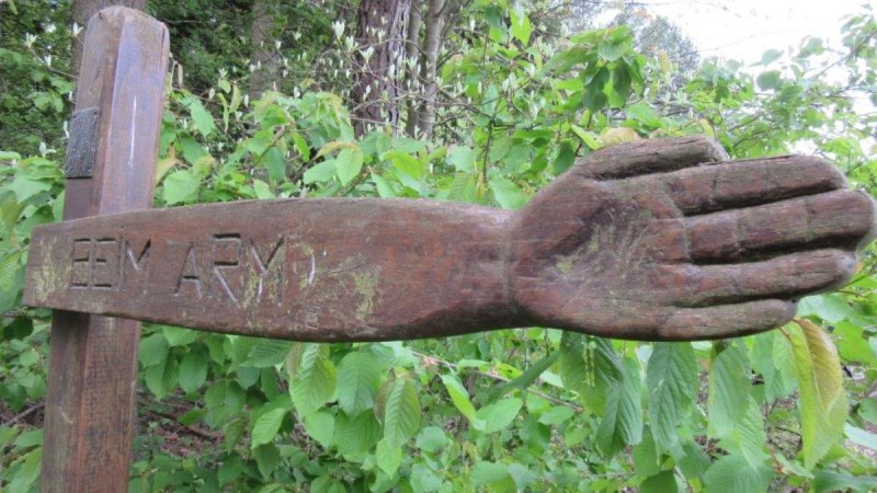 Holzskulptur eines ausgestreckten Arms mit der Inschrift 'BEIM ARM' in einem grünen Waldgebiet., © Natur.Nah. Schönbuch & Heckengäu Holzskulptur eines ausgestreckten Arms mit der Inschrift 'BEIM ARM' in einem grünen Waldgebiet., © Natur.Nah. Schönbuch & Heckengäu