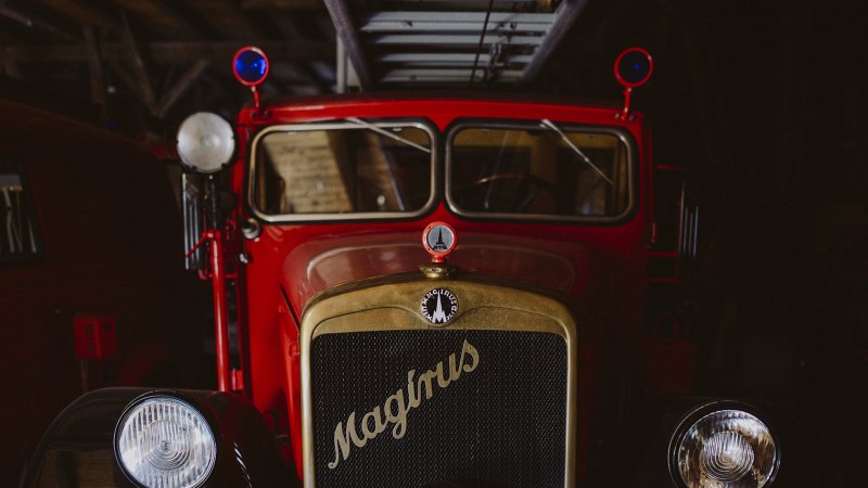 Ein rotes, historisches Feuerwehrfahrzeug der Marke Magirus im Feuerwehrmuseum Schwäbisch Hall, mit blauen Rundlichtern und einem goldenen Kühlergrill., © Nico Kurth