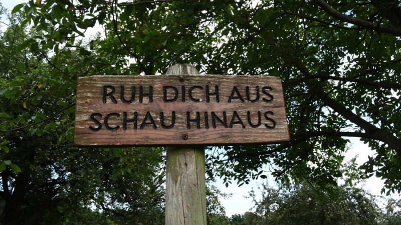 Holzschild mit der Aufschrift 'Ruh dich aus, schau hinaus' in einer gr&uuml;nen, bewaldeten Umgebung., &copy; N&uuml;rtingen - Stuttgart-Marketing GmbH