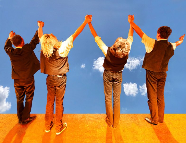 Vier Personen stehen auf einer Bühne, halten sich die Hände und blicken in den blauen Himmel mit Wolken., © Stadtverwaltung Schorndorf