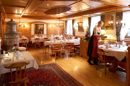 Gemütliches Restaurant mit Holzmöbeln, Teppich und gedeckten Tischen. Eine Bedienung in traditioneller Kleidung serviert an einem Tisch., © Jeanette Bender Gemütliches Restaurant mit Holzmöbeln, Teppich und gedeckten Tischen. Eine Bedienung in traditioneller Kleidung serviert an einem Tisch., © Jeanette Bender