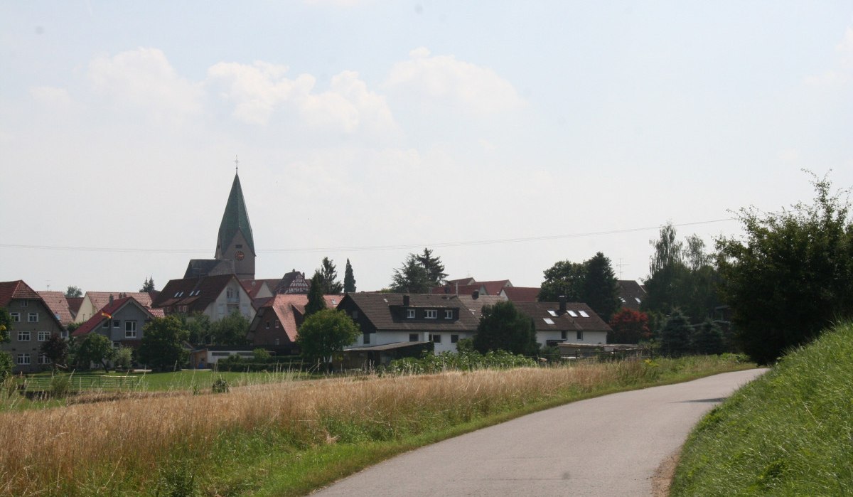 Ein Dorf mit einer Kirche im Zentrum, umgeben von Wohnhäusern, Feldern und Bäumen unter einem leicht bewölkten Himmel., © Natur.Nah. Schönbuch & Heckengäu
