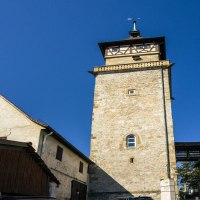 Der Hochwachturm in Waiblingen steht zwischen zwei Fachwerkhäusern unter klarem, blauem Himmel., © SMG, Sarah Schmid Der Hochwachturm in Waiblingen steht zwischen zwei Fachwerkhäusern unter klarem, blauem Himmel., © SMG, Sarah Schmid
