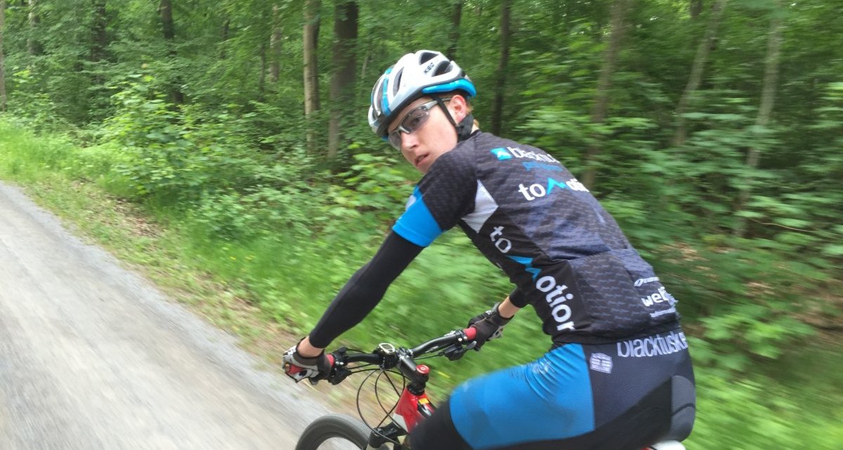 Ein Radfahrer in sportlicher Kleidung f&auml;hrt auf einem Waldweg durch einen gr&uuml;nen Wald., &copy; www.pro-cycl.de