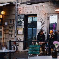 Au&szlig;enansicht des Caf&eacute;s 'Suessholz' im Leonhardsviertel. Menschen sitzen drau&szlig;en, unterhalten sich. Graffiti an den W&auml;nden, Neonlicht im Fenster., &copy; Stuttgart-Marketing GmbH, Alwin Maigler