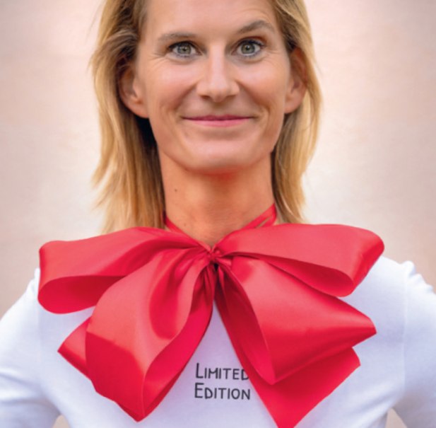 Frau mit roter Schleife um den Hals, trägt ein weißes Shirt mit der Aufschrift 'Limited Edition'. Hintergrund ist neutral., © Theaterwerkstatt Schwäbisch Gmünd e.V.