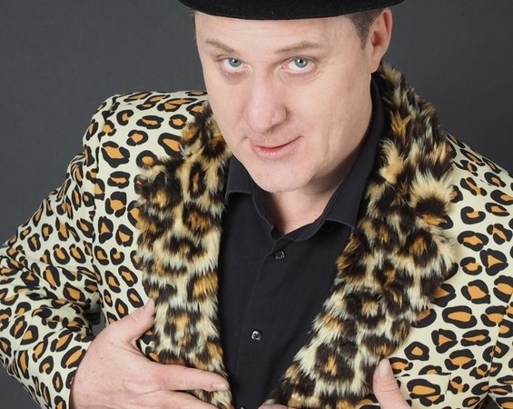 Person mit schwarzem Hut und Leopardenjacke posiert vor grauem Hintergrund., © Mauerwerk GmbH Person mit schwarzem Hut und Leopardenjacke posiert vor grauem Hintergrund., © Mauerwerk GmbH