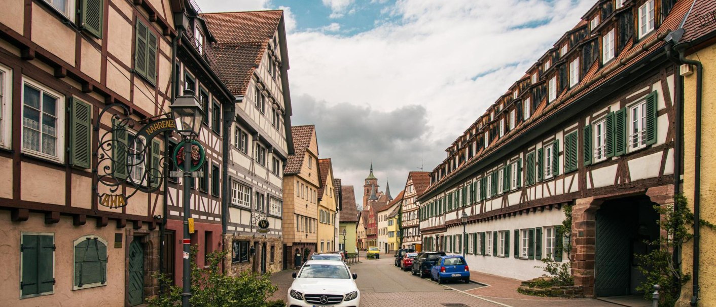 Fachwerkhäuser säumen eine Straße in der Altstadt von Weil der Stadt. Autos parken entlang der Straße, während Wolken den Himmel bedecken., © Stuttgart-Marketing GmbH, Sarah Schmid Fachwerkhäuser säumen eine Straße in der Altstadt von Weil der Stadt. Autos parken entlang der Straße, während Wolken den Himmel bedecken., © Stuttgart-Marketing GmbH, Sarah Schmid