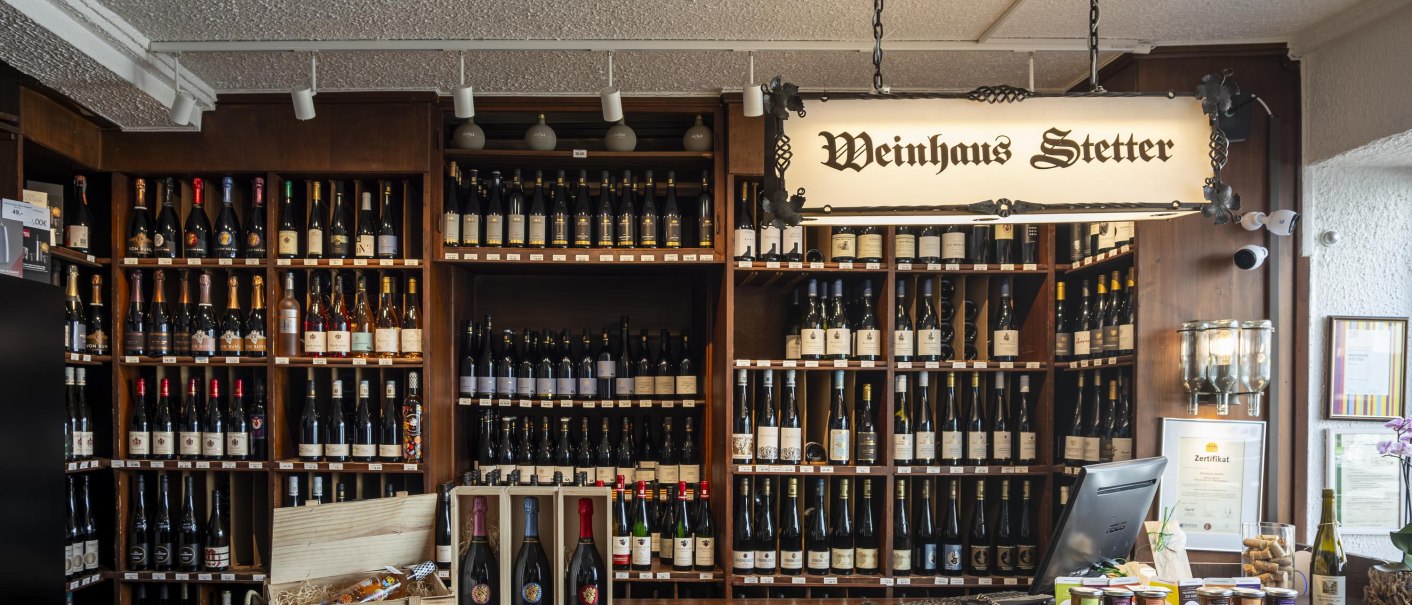 Theke im Weinhaus Stetter mit Regalen voller Weinflaschen und einem hölzernen Tresen. Ein Schild mit der Aufschrift 'Weinhaus Stetter' hängt von der Decke., © Stuttgart Marketing GmbH, Sarah Schmid