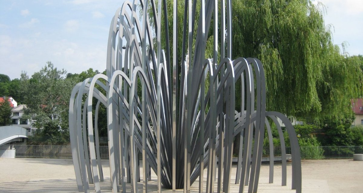 Moderne Skulptur aus gebogenen Metallstreben, die in einem Pavillon-ähnlichen Muster angeordnet sind, umgeben von Bäumen und einem klaren Himmel., © Remstal Tourismus e.V. Moderne Skulptur aus gebogenen Metallstreben, die in einem Pavillon-ähnlichen Muster angeordnet sind, umgeben von Bäumen und einem klaren Himmel., © Remstal Tourismus e.V.